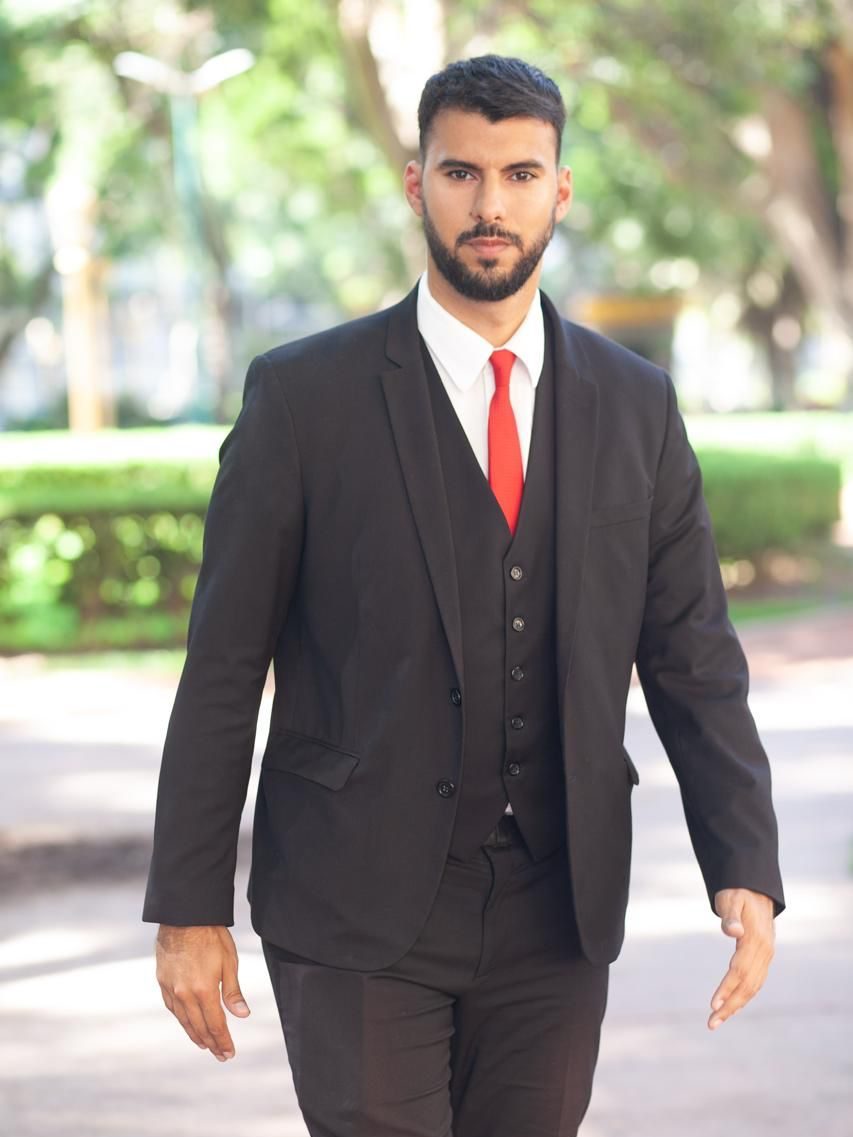 El Dr. Agustín Simonelli caminando de traje por un parque.